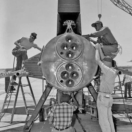 Engineers in overalls working on a rocket engine on a test stand